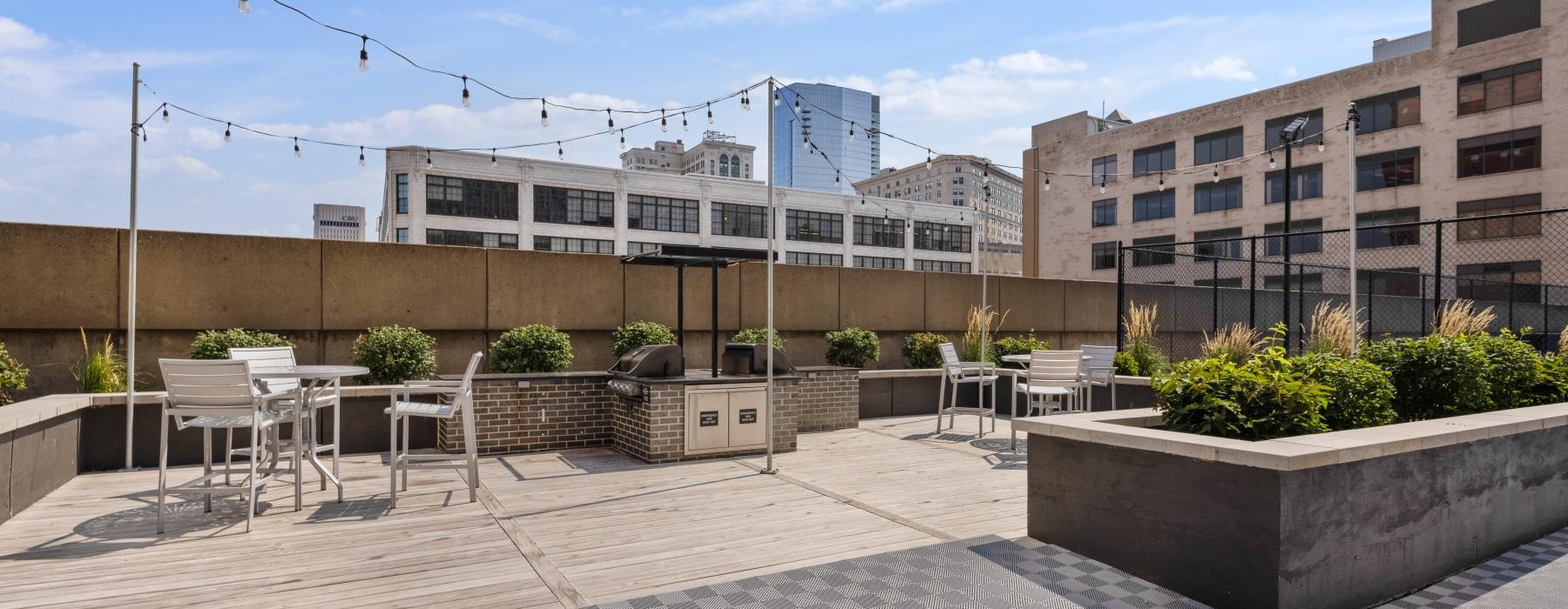 a rooftop courtyard with tables and chairs and plants in front of a building